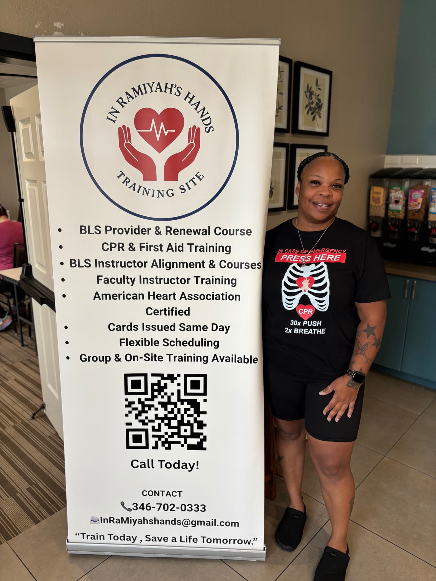 Training Site Coordinator standing beside the In RaMiyah's Hands banner